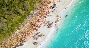 Rugged coastline at Castle Rock in Dunsborough Western Australia showing granite boulder formations, white sandy beach and turquoise Geographe Bay waters with rolling waves