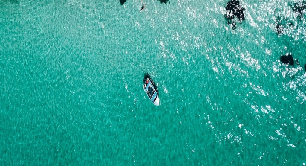 Bird's eye view of a lone boat on the glassy turquoise water at Eagle Bay, WA
