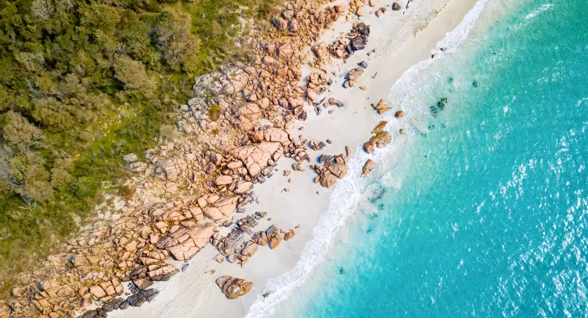 Aerial view of pristine Meelup beach in Dunsborough with crystal-clear turquoise waters, white sand, and scattered granite boulders along the Western Australian coastline perfect for swimming and relaxation