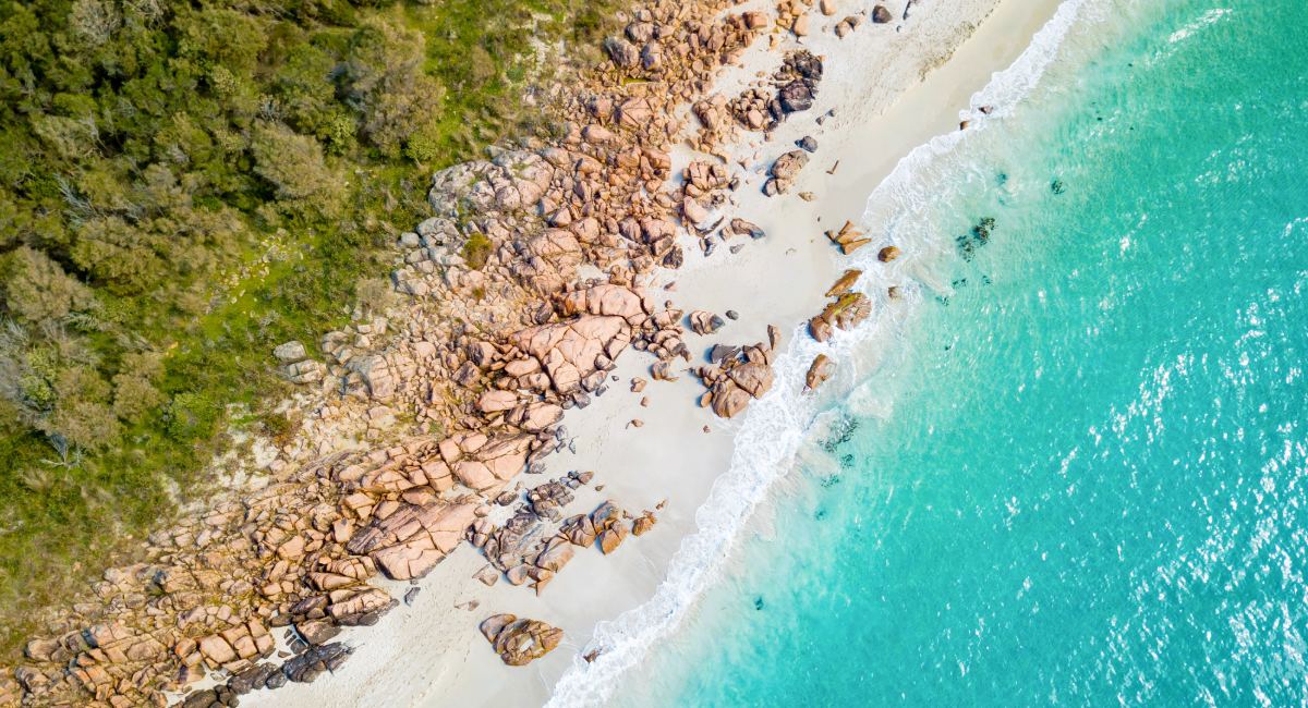 Aerial view of pristine Meelup beach in Dunsborough with crystal-clear turquoise waters, white sand, and scattered granite boulders along the Western Australian coastline perfect for swimming and relaxation