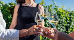 Family toasting with white wine glasses at Margaret River winery during autumn harvest season with golden sunlight and vineyard in background