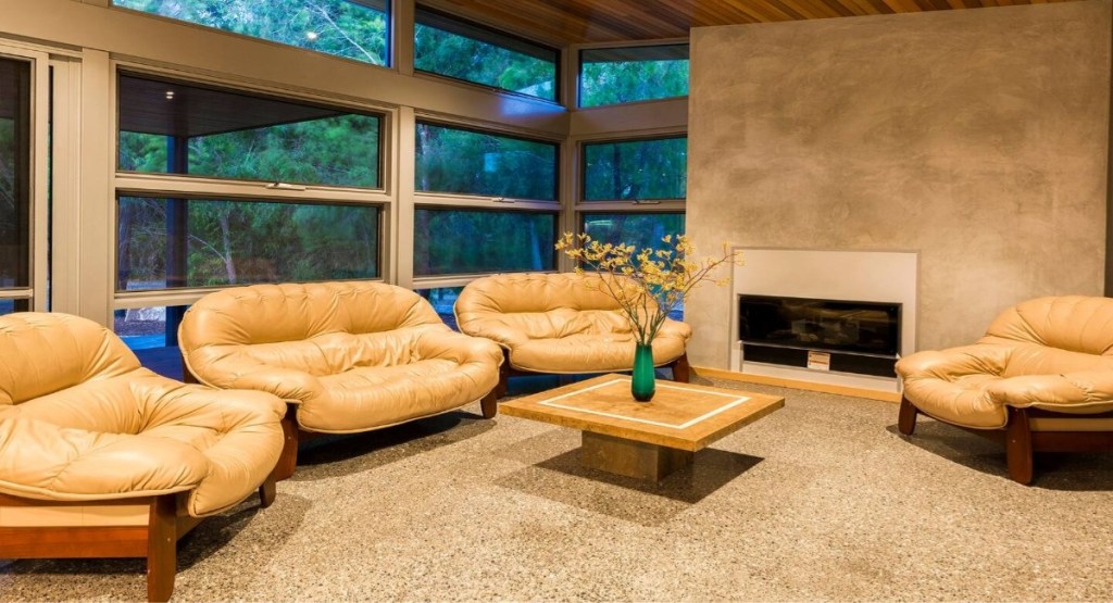 Dunsborough holiday rental living room with leather sofas, fireplace, and native bush views through large windows